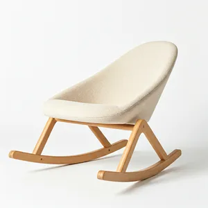 Modern sculptural baby rocker with sleek wooden base and cream fabric seat on minimalist white background